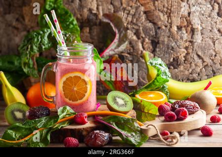 Healthy smoothie with fruits,berry, dried fruit and chard leaves in a mason jar mug on wooden background. Healthy eating concept. Stock Photo