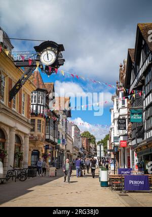 A view looking east up the hill of the High Street in historic Winchester, Hampshire, UK under the iconic Victorian iron clock. Winchester was an anci Stock Photo