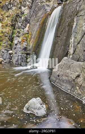 A waterfall crashes down a vertical cliff, on the coast at Speke's Mill Mouth, near Hartland Quay, the Atlantic coast of Devon, Great Britain. Stock Photo