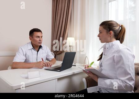 Two doctors man and woman talking, looking at computer screen Stock Photo