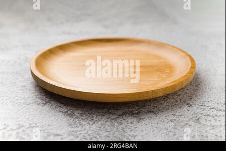 Wooden plate on a white stone background. handmade cooking utensils Stock Photo