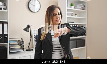 Middle eastern woman business worker looking watch with unhappy expression at office Stock Photo