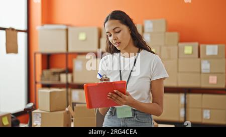 African american woman ecommerce business worker writing on document checking pacakges at office Stock Photo
