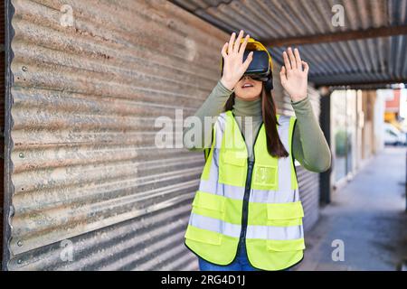 Young beautiful hispanic woman architect using virtual reality glasses at street Stock Photo