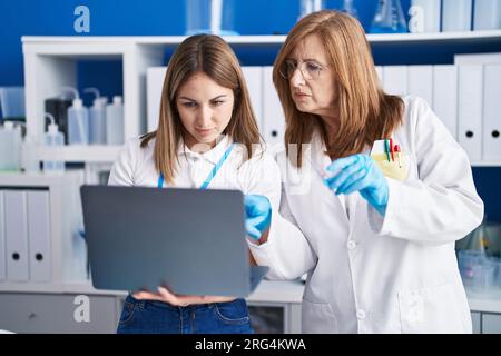 Mother and daughter scientists using laptop working at laboratory Stock Photo