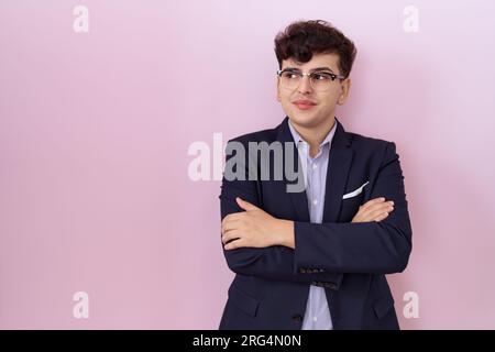 Young non binary man with beard wearing suit and tie smiling looking to the side and staring away thinking. Stock Photo
