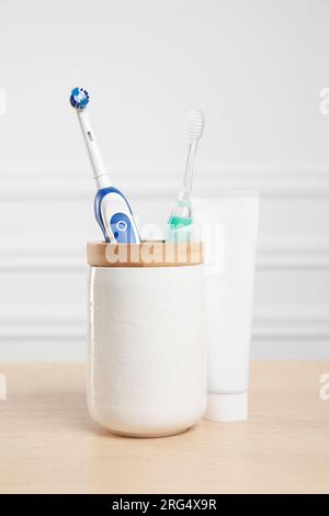 Electric toothbrushes and tube of paste on wooden table Stock Photo