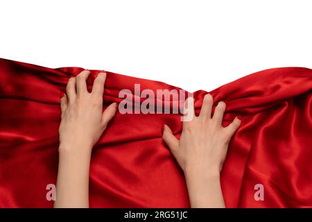 A woman's hand with red nails is trying to rip off  red silk fabric. Stock Photo