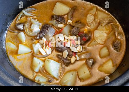 Beef massaman curry made with slow cooked beef, spices and potatoes, garnished with peanuts and chilis. Stock Photo