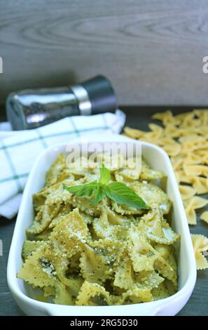 Bowl of Delectable Homemade Farfalle Pasta with Pesto Sauce on Kitchen Table Stock Photo