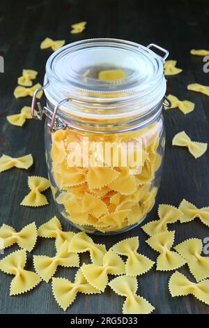 Dried Farfalle Pasta in a Glass Jar with Some Scattered Around Stock Photo