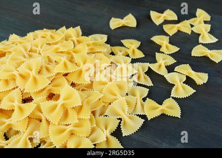 Pile of Dried Bow-tie Shaped Pasta Called Farfalle on Black Wooden Background Stock Photo