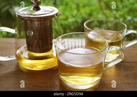 Closeup of glasses of hot tea with a tea kettle on wooden table Stock Photo