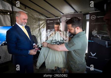 Kyiv, Ukraine. 06th Aug, 2023. Ukrainian President Volodymyr Zelenskyy, right, is presented with a fighter pilots jacket with the logo of the F-16 Fighting Falcon aircraft while visiting the flight simulation training system provided by the Czech Republic on Air Force Day, August 6, 2023 in Kyiv, Ukraine. Credit: Pool Photo/Ukrainian Presidential Press Office/Alamy Live News Stock Photo