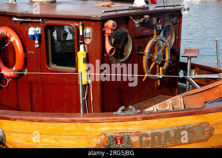 Old-fashioned mahogany wood built boat cockpit and steering wheel, Motlawa river, Gdansk, Poland, Europe, EU Stock Photo