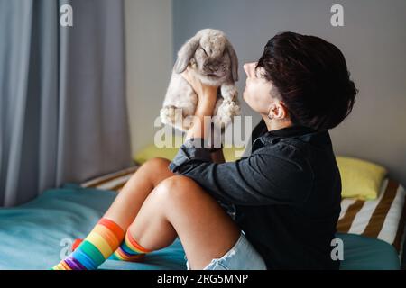 Woman with rabbit having tender moment at home - Owner and pet friendship relationship - Main focus on girl head Stock Photo