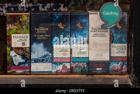 Portree Isle of  Skye, Scotland, UK. 5 June 2023.  Boxes of Scotch whiskey onsale  from shop window display on the Portree town waterfron,t Isle of Sk Stock Photo