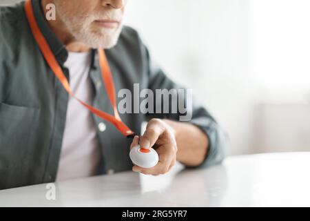 Cropped shot of senior man pushing emergency button hung on his chest Stock Photo