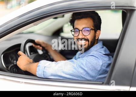 Excited eastern guy going to office in morning, driving car Stock Photo