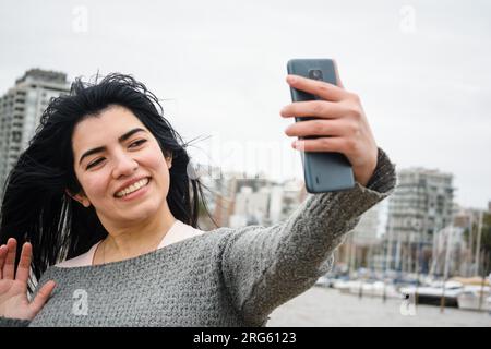 Latin girl taking a picture with her mobile phone. Teenager in a video call  with her