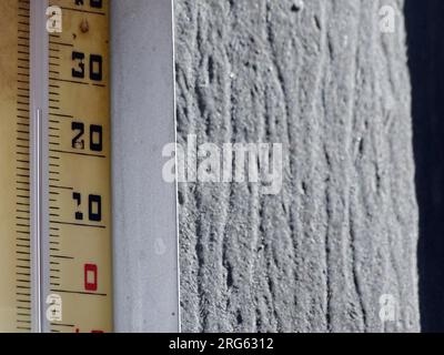 Vintage Thermometer Reading 25-26 Degrees Celsius: A Tropical Summer's Measure of Heat, Weather Forecast on Weathered Wood Under a Clear Sky Stock Photo