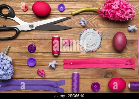 Sewing supplies with Easter eggs and flowers on wooden background Stock Photo