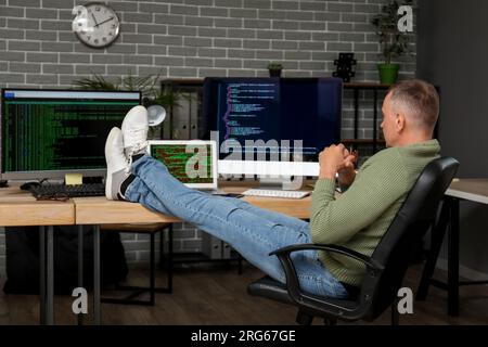 Mature male programmer sitting in office at his workplace Stock Photo