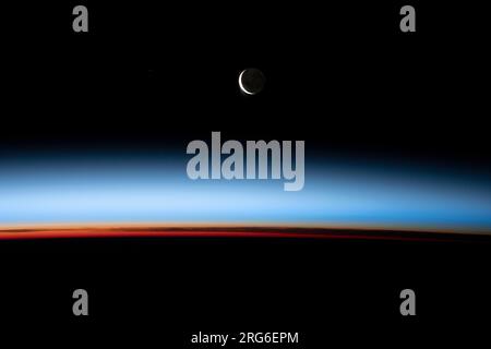 A crescent moon hovering above an orbital sunset. Stock Photo