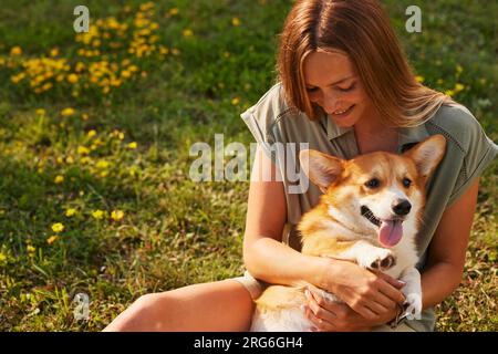 young girl hugging pembroke welsh corgi in the park in sunny weather, happy dogs concept Stock Photo