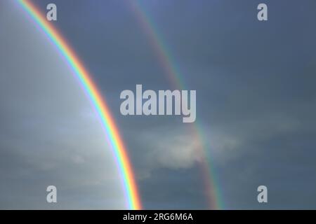 Magical double rainbow on the background of blue sky just after rain during sunset Stock Photo