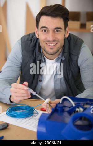 electrician using screwdriver on electrical junction box Stock Photo