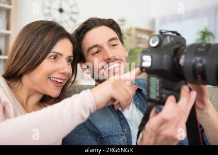 couple at home reviewing photos on camera screen Stock Photo
