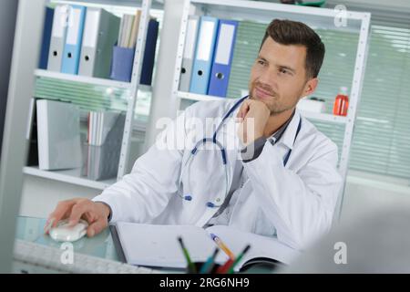 handsome male doctor smiling while using computer Stock Photo