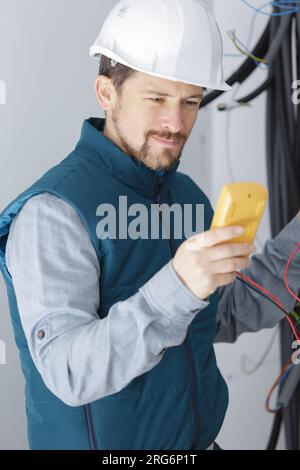 electrician measuring voltage in distribution board Stock Photo
