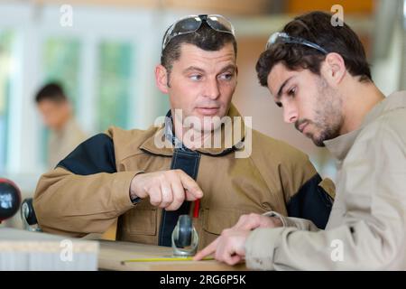 two carpenters discussing something in workshop Stock Photo
