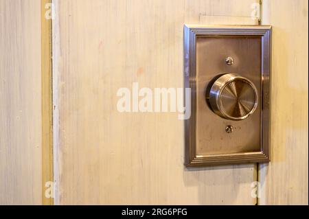 Closeup of metal rotary dimmer knob for overhead lights on interior wall Stock Photo
