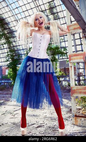Portrait of the beautiful laughing freak girl. Cute smiling woman wearing colorful corset, tights and tutu skirt in forsaken place Stock Photo