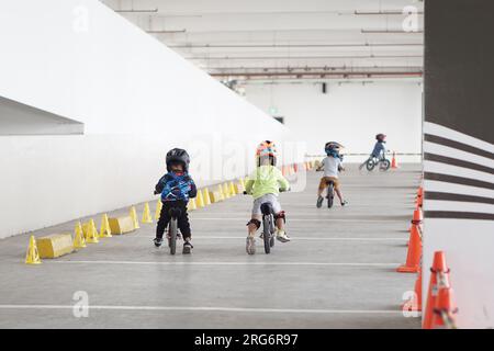 kids from 2-5 years old races on balance bike in a parking area, back view, behind view shoot. Stock Photo