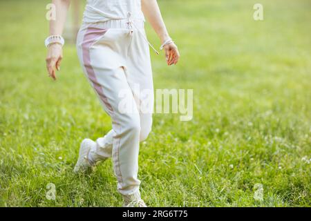 Summer time. Closeup on female in white shirt walking in the meadow outside in nature. Stock Photo