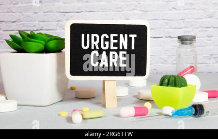 White notepad with the words URGENT CARE and a stethoscope on a blue background. Medical concept. Stock Photo