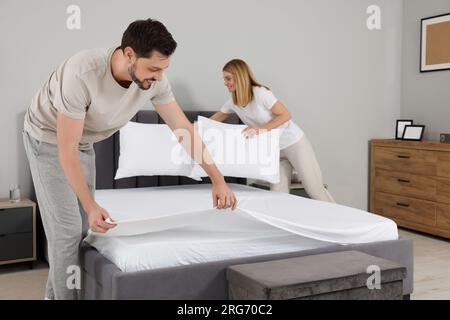 Couple changing bed linens in room. Domestic chores Stock Photo