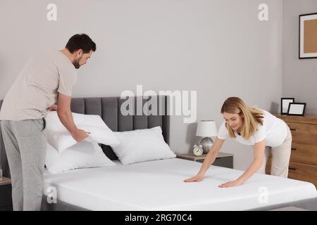 Couple changing bed linens in room. Domestic chores Stock Photo