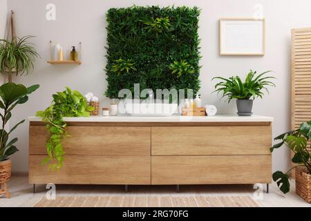 Green artificial plants, vanity and different personal care products in  bathroom Stock Photo - Alamy