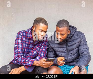 Two teens using mobile phone while relaxing in a park, Stock Photo