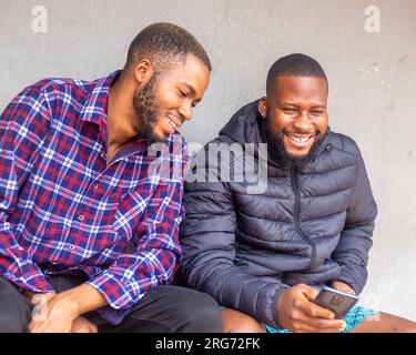 Two teens using mobile phone while relaxing in a park, Stock Photo