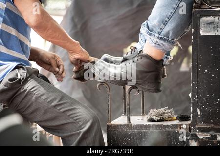 Latino man works shining shoes on the streets of Mexico Stock Photo