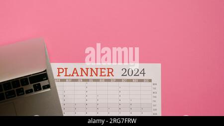 2024 Planner with computer laptop. Top view with copy space. Stock Photo