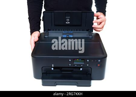 Person lifts the lid of the printer's rear tray preparing the device for a printing task. Stock Photo