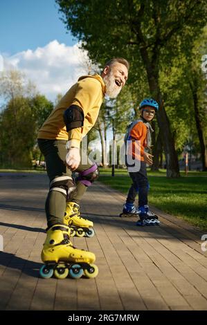 Happy grandfather and grandson on roller skates posing for camera Stock Photo