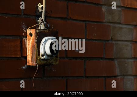 Old worn electricity switch on exterior brick wall, selective focus Stock Photo